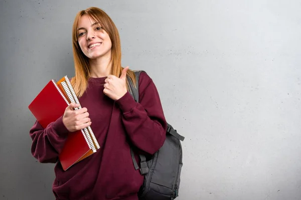 Studentin mit erhobenem Daumen auf grauem Hintergrund — Stockfoto