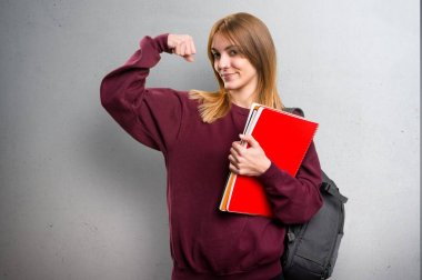 Öğrenci kadın gri arka plan üzerinde güçlü bir jest yapma