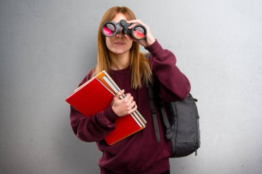 Öğrenci kadın gri arka plan üzerinde dürbün ile