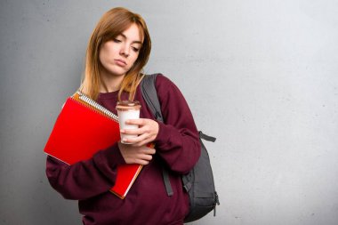 Bir fincan kahve gri arka plan üzerinde tutan öğrenci kadın