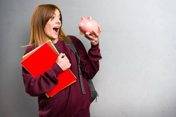 Studentka žena držící prasátko na šedém pozadí — Stock fotografie