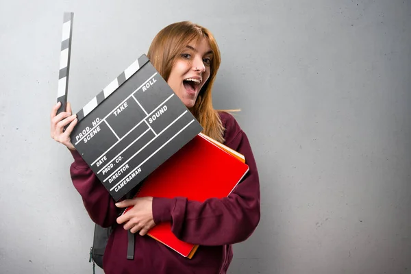 Siswa wanita memegang clapperboard di latar belakang abu-abu — Stok Foto