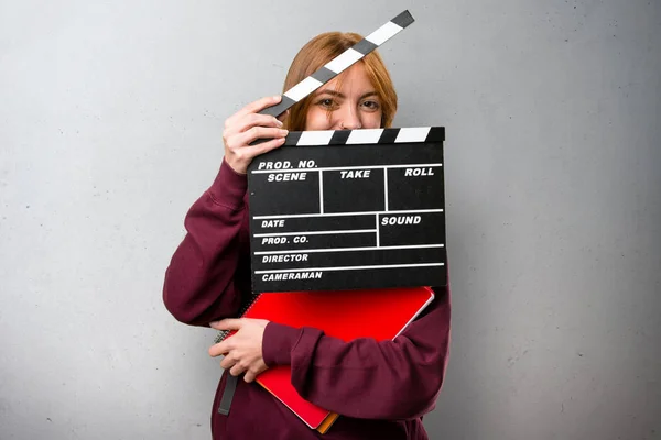 Siswa wanita memegang clapperboard di latar belakang abu-abu — Stok Foto