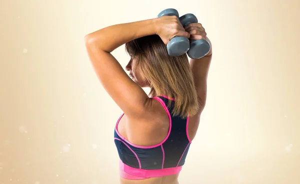 Deporte mujer haciendo levantamiento de pesas sobre fondo ocre —  Fotos de Stock