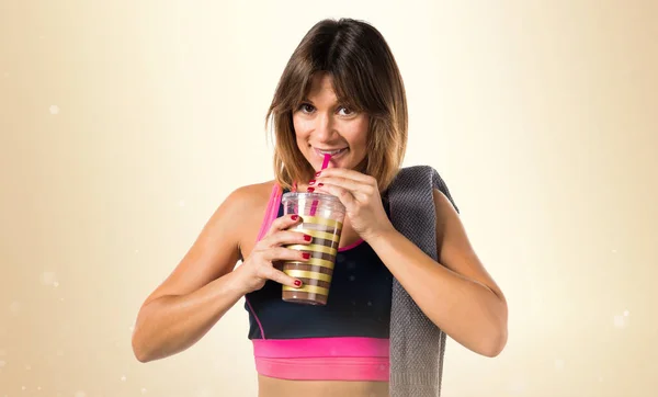 Sportlerin trinkt Sportgetränk auf ockerfarbenem Hintergrund — Stockfoto