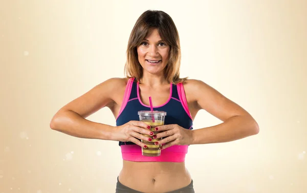 Atleta donna in possesso di una bevanda sportiva su sfondo ocra — Foto Stock
