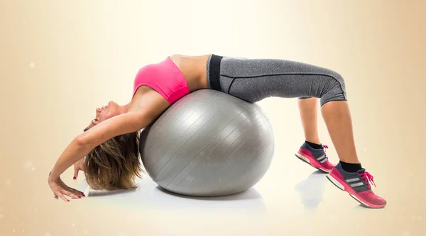 Sportovní žena dělat sport s fit ball na okrové backg — Stock fotografie