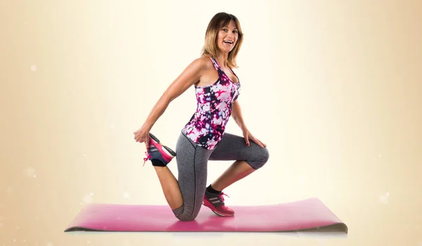 Sport vrouw uitrekken op mat op okergeel achtergrond — Stockfoto