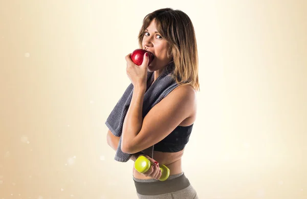 Sport donna mangiare una mela su sfondo ocra — Foto Stock