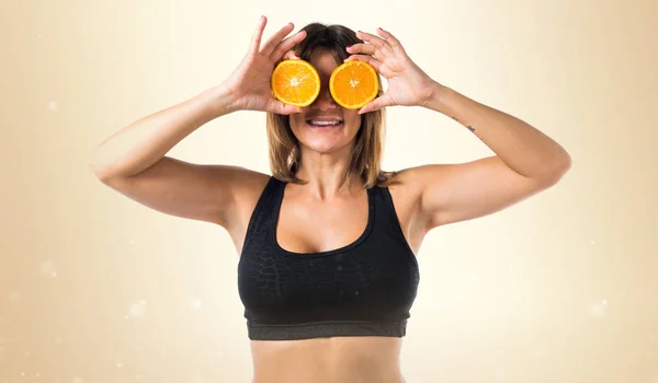 Deporte mujer usando rebanadas de naranja como gafas sobre fondo ocre —  Fotos de Stock