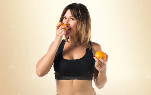 Deportiva comiendo una naranja sobre fondo ocre —  Fotos de Stock