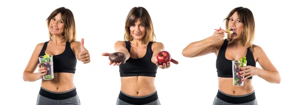 Sport woman holding an apple in one hand and donut in other hand — Stock Photo, Image