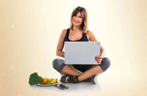 Nutritionist working on-line with her laptop on ocher background — Stock Photo, Image