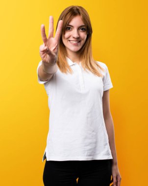 Güzel genç kız üç sarı zemin üzerine sayma