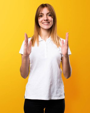 Bir şey sarı arka plan üzerinde tutan güzel genç kız