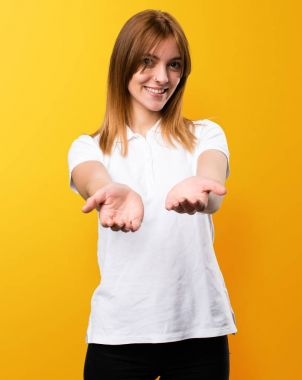 Bir şey sarı arka plan üzerinde tutan güzel genç kız