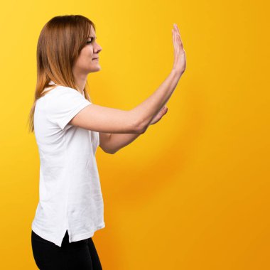 Güzel genç kız bir şey üzerinde sarı arka plana iterek