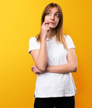 Güzel genç kız sarı arka plan üzerinde düşünme