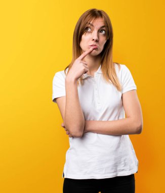 Güzel genç kız sarı arka plan üzerinde düşünme