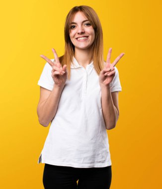 Güzel genç kız yapma zafer jest Sarı zemin üzerine