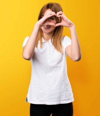 Güzel genç kız üzerinde sarı bac elleri ile bir kalp yapma