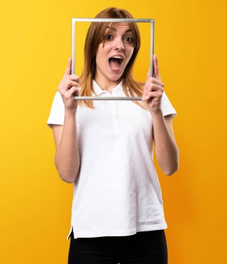 Framework üzerinde sarı backgrou ile sürpriz güzel genç kız