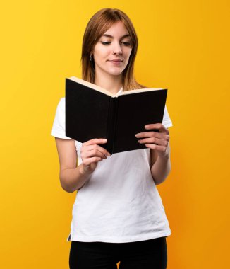 Güzel genç kız sarı zemin üzerine kitap okuma