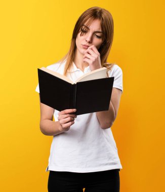 Güzel genç kız sarı zemin üzerine kitap okuma