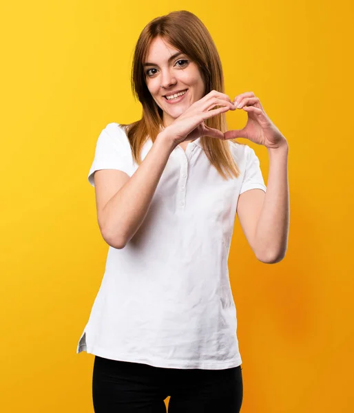 Menina bonita fazendo um coração com as mãos no bac amarelo — Fotografia de Stock