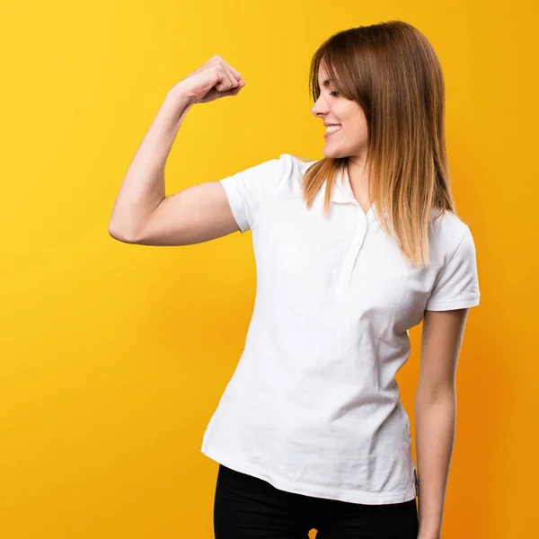 Beautiful young girl making strong gesture on yellow background — Stock Photo, Image