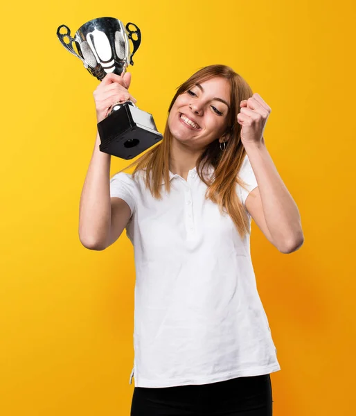 Feliz menina bonita segurando um troféu no fundo amarelo — Fotografia de Stock
