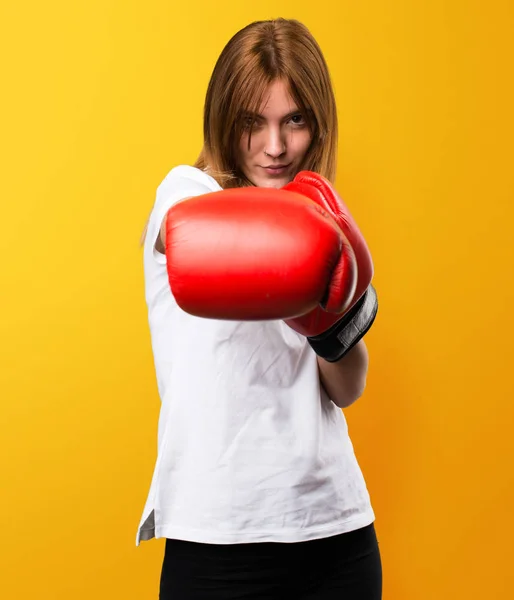 Hermosa joven con guantes de boxeo sobre fondo amarillo — Foto de Stock