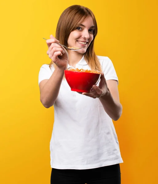 Счастливая девочка ест каши из миски на желтом — стоковое фото