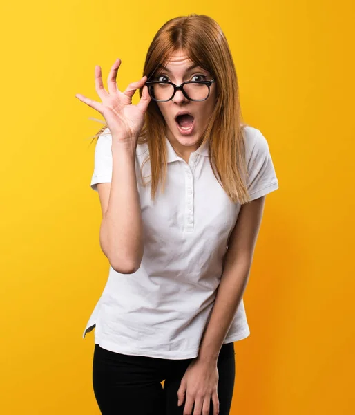 Surprised Beautiful young girl with glasses on yellow background — Stock Photo, Image