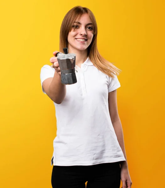 Glücklich schöne junge Mädchen hält eine Kaffeekanne auf gelbem Backgr — Stockfoto