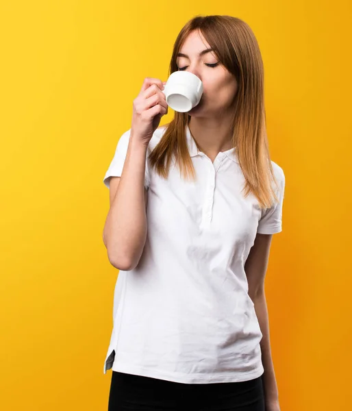 Krásná mladá dívka držící šálek kávy na žluté poza — Stock fotografie