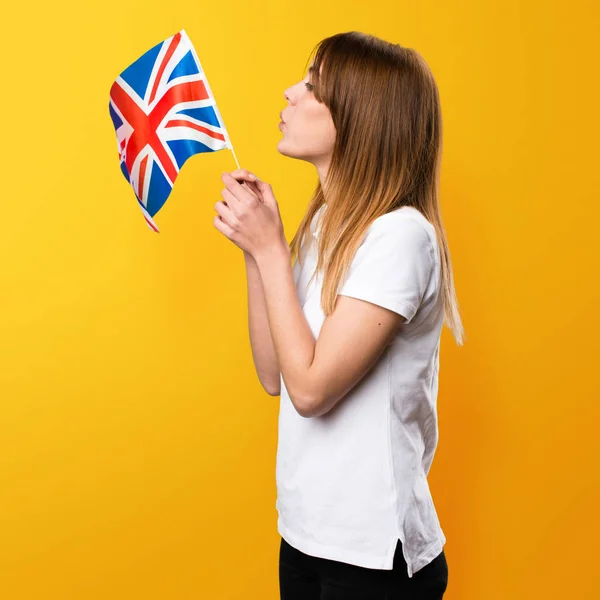 Krásná mladá dívka drží vlajku Spojeného království na žluté ba — Stock fotografie