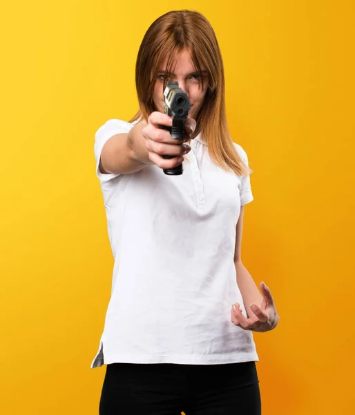 Hermosa joven sosteniendo una pistola sobre fondo amarillo — Foto de Stock