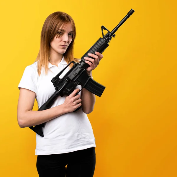 Bella ragazza in possesso di un fucile su sfondo giallo — Foto Stock