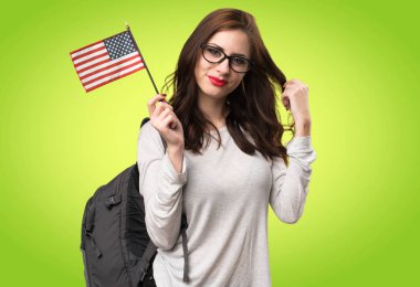 Bir Amerikan bayrağı renkli arka plan üzerinde tutan öğrenci kadın