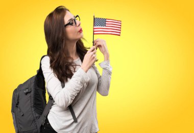Bir Amerikan bayrağı renkli arka plan üzerinde tutan öğrenci kadın