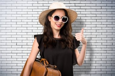 Güzel genç kız bir bavul ve bir BRI üzerinde başparmak ile