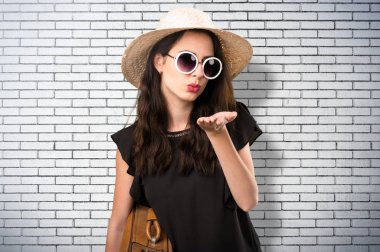 Bir tuğla üzerinde bir öpücük gönderme bavulla güzel genç kız 