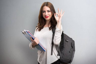 Ok işareti yapma öğrenci kadın dokulu arka plan