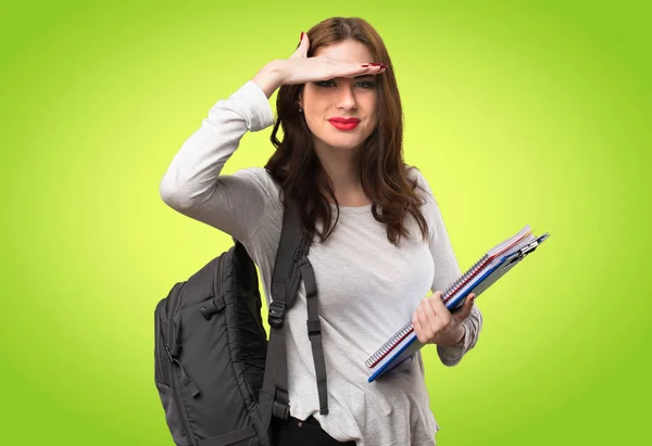 Studerande kvinna visar något på färgstarka bakgrund — Stockfoto