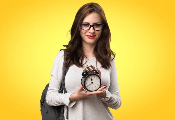 Student woman holding vintage clock on colorful background — Stock Photo, Image