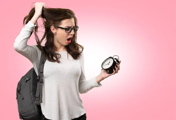 Frustrated student woman holding vintage clock on colorful backg — Stock Photo, Image
