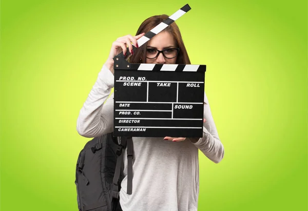 Student woman holding a clapperboard on colorful background — Stock Photo, Image