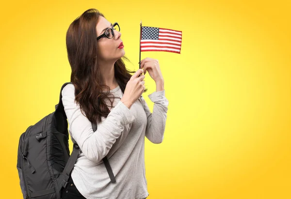 Студентська жінка тримає американський прапор на барвистому фоні — стокове фото