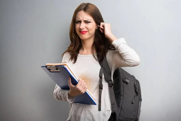 Student vrouw die betrekking hebben op haar oren op gestructureerde achtergrond — Stockfoto